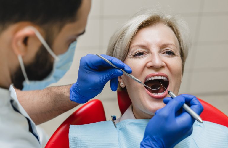 Opened mouth during stomatology checkup. Male dentist orthodont stomatologist curing operating filling tooth teeth mouth cavity to female patient.